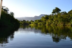 een rivier met bomen en bergen op de achtergrond bij Tropical Paradise in Ubatuba