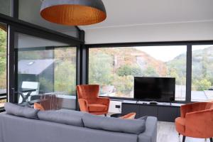 een woonkamer met een bank en stoelen en een tv bij In Monte in Vresse-sur-Semois