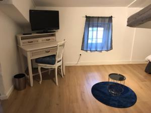 a room with a desk with a television and a chair at Ô Petit Nice in Neuville-sur-Saône