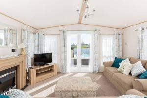 un soggiorno con un divano e una TV di Thumper Lodge - Luxury lodge with Hot Tub a South Cerney