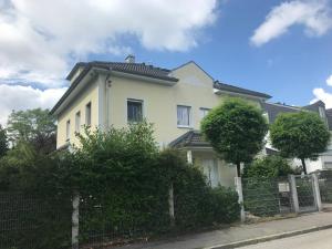 uma casa branca com uma cerca à frente. em Helle Souterrainwohnung mit Komfort em Munique