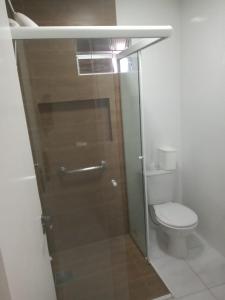 baño con aseo y puerta de ducha de cristal en Residencial Mariano 4 - Vista para praia e Mar en Florianópolis