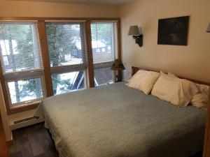 a bedroom with a bed and a bunch of windows at The Woods Inn in Inlet