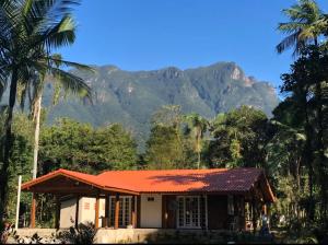 a house with palm trees and mountains in the background at Chácara Porto Bello - Casa com Piscina em Morretes in Morretes
