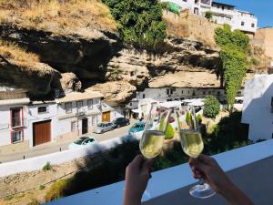 una persona sosteniendo dos copas de vino en una cornisa en Casa Bajo la Roca, en Setenil