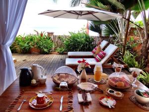 a table with plates of food and an umbrella at Pousada Sagi Iti in Baía Formosa