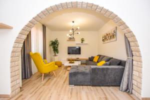an arched living room with a gray couch and yellow chairs at Apartmani Plazibat in Mandre