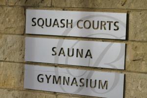 a sign for a tennis court on a brick wall at Bentleys Motor Inn in Palmerston North