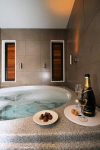bañera de hidromasaje con 2 platos de comida y copas de vino en Bentleys Motor Inn en Palmerston North