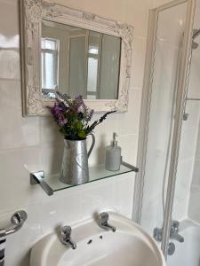 a bathroom sink with a mirror and a vase with flowers at Beautiful 2 bedroom flat in Camden in London