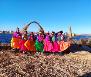 a group of people posing for a picture in front of the water at Titicaca in Puno