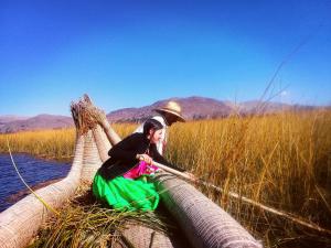 uma mulher está sentada em cima de uma rede na água em Titicaca em Puno