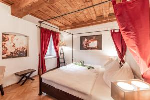 a bedroom with a canopy bed with red curtains at NaturparkResort Haus der Hoamatlegenden in Landl
