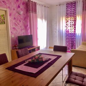 sala de estar con mesa de comedor y cortinas rosas en Appartamento Il Portico, en Malesco