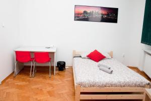 a bedroom with a bed and a desk and two red chairs at Ionia Apartment - Stary Rynek- in Poznań