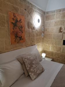 een slaapkamer met een wit bed en een schilderij aan de muur bij Le camelie in Altamura