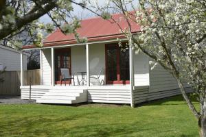 una pequeña casa blanca con techo rojo en Terracotta Lodge & Cottages en Carterton