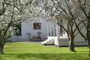 a white house with a table and some trees at Terracotta Lodge & Cottages in Carterton