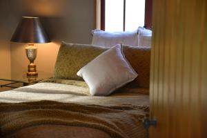 sypialnia z łóżkiem z poduszkami i oknem w obiekcie Terracotta Lodge & Cottages w mieście Carterton