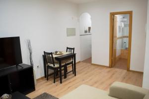 sala de estar con mesa, sillas y TV en Apartamenticos Boggiero IV, en Zaragoza
