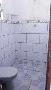 a bathroom with a toilet and a white tiled wall at Casa Rustica Milho Verde in Milho Verde