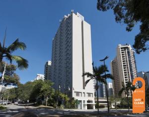 a tall white building in a city with palm trees at Quality Suites Alphaville in Barueri