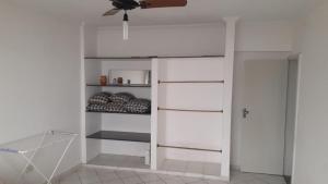 ein Schlafzimmer mit weißen Wänden und einem Deckenventilator in der Unterkunft Apartamento frente a praia in Peruíbe