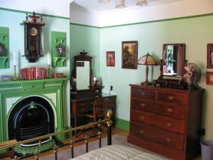 a room with a fireplace and a dresser and a mirror at Gower Manor Historic Bed & Breakfast in St. John's