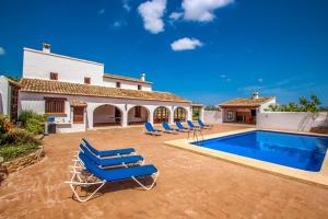une villa avec une piscine et des chaises longues bleues dans l'établissement Finca Pere - panoramic hillside holiday house in Benissa, à Teulada