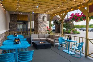 eine Terrasse mit blauen Tischen, einem Sofa und einer Feuerstelle in der Unterkunft Ramkota Hotel - Casper in Casper