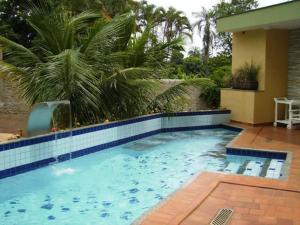 einen großen Pool mit Fliesenboden und ein Haus in der Unterkunft ARQ Inn Hotel in Ribeirão Preto