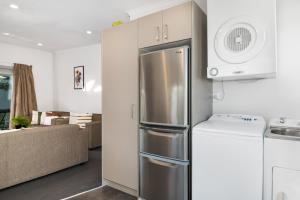 a kitchen with a stainless steel refrigerator next to a living room at Two Tree Motel & Lodge in Blenheim