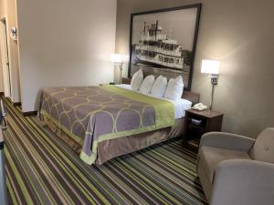 a hotel room with a bed and a chair at Super 8 by Wyndham Hernando in Hernando