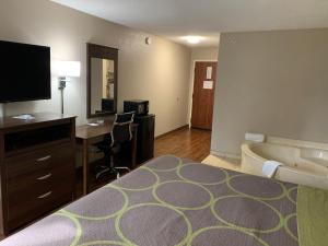 a hotel room with a bed and a desk and a tub at Super 8 by Wyndham Hernando in Hernando