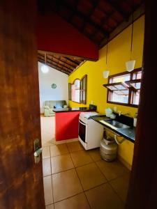 uma cozinha com paredes amarelas e um balcão vermelho em Alto do Marinas em Angra dos Reis