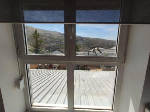 a window with a view of a dog on a deck at ALCAZABA ELITE in Sierra Nevada
