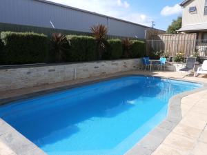 a swimming pool with blue water in a yard at Sovereign Views Apartments in Ballarat