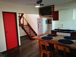 a kitchen with a wooden table and a red door at Zen Spa Houses in São Miguel dos Milagres