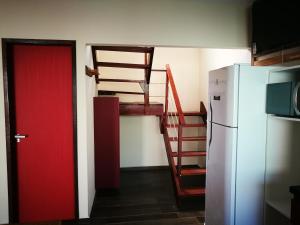 a room with a refrigerator and a red door at Zen Spa Houses in São Miguel dos Milagres