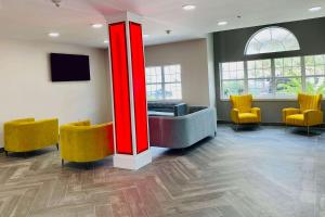 a waiting room with yellow chairs and a red pillar at Super 8 by Wyndham San Antonio Airport North in San Antonio