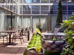 un patio avec des tables et des chaises dans un bâtiment dans l'établissement Residence Mercure Paris La Defense Grande Arche, à Nanterre