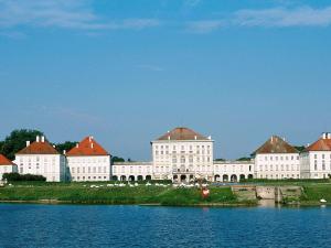 a large white building with red roofs next to a body of water at ibis Hotel München Garching in Garching bei München