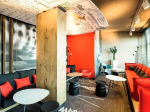 a restaurant with tables and couches and red chairs at ibis Hotel München Garching in Garching bei München