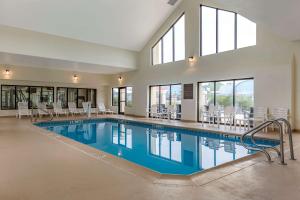 a large swimming pool with chairs and tables and windows at Comfort Inn & Suites Warsaw near US-30 in Warsaw
