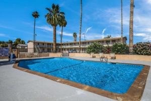 a swimming pool in front of a building with palm trees at Rodeway Inn & Suites Blythe I-10 in Blythe