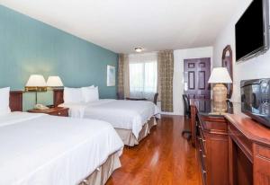 a hotel room with two beds and a flat screen tv at Days Inn & Suites by Wyndham Sunnyvale in Sunnyvale +19 photos