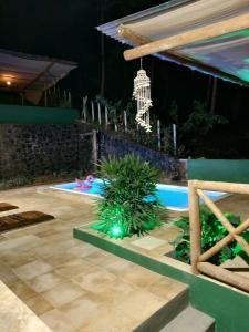 un patio trasero con piscina por la noche con una lámpara de araña en Pousada Bicho Preguiça, en Itacaré
