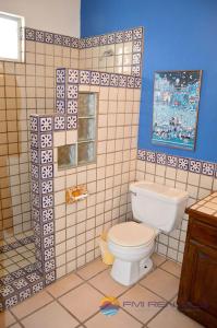 a bathroom with a toilet and a blue wall at Casa Chapman by FMI Rentals in Puerto Peñasco