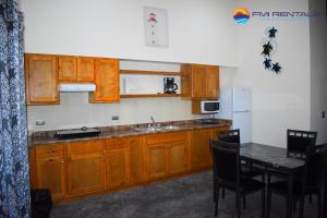 una cocina con armarios de madera y una mesa con sillas. en Turtle Studio en Puerto Peñasco