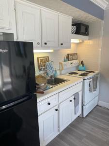 a kitchen with white cabinets and a black refrigerator at Daytona Beach Inn Resort in Daytona Beach